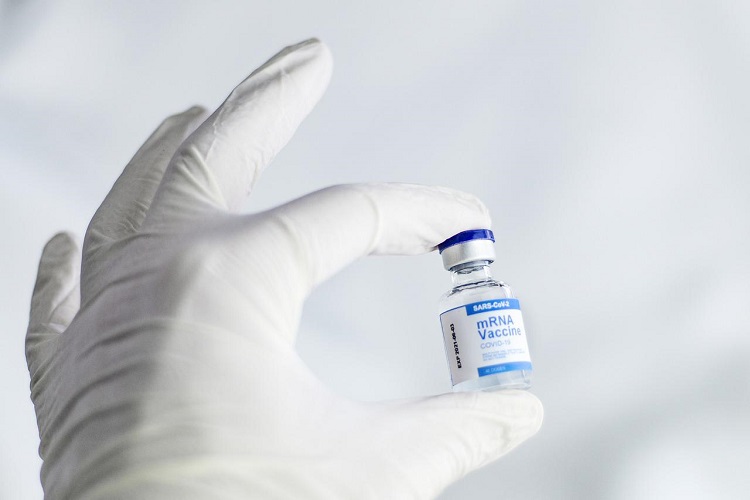 Vial of COVID vaccine held in white gloved hand